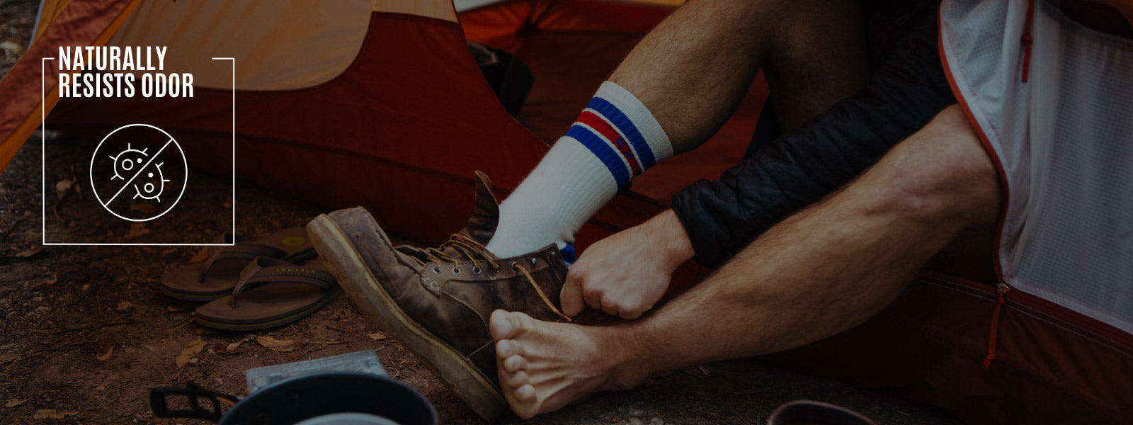 Backpacker sitting in tent putting on Cloudline socks and leather hiking boots. 
