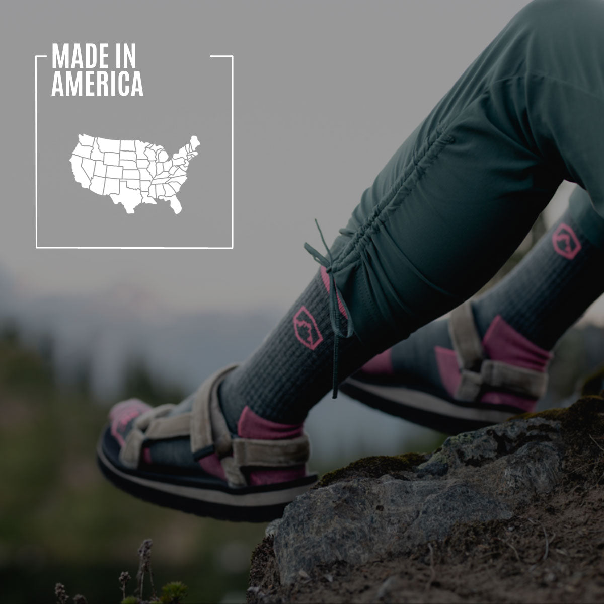 Hiker wearing Cloudline socks sitting on rock above lake. 