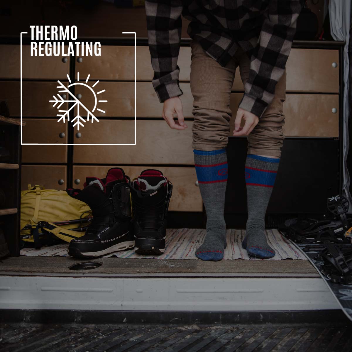 Snowboarder wearing Cloudline socks surrounded by gear in camper van. 