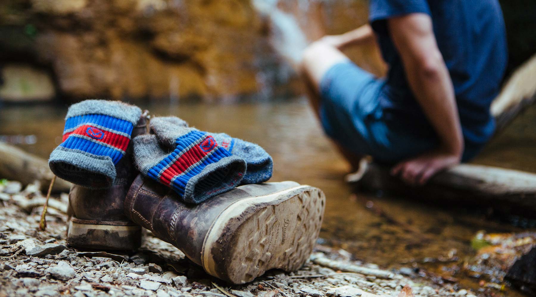 hiker sitting next to small waterfall with Cloudline socks off and ready to be washed on the trail. 
