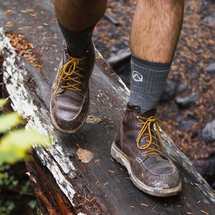Hiker wearing Cloudline socks crossing a log bridge.