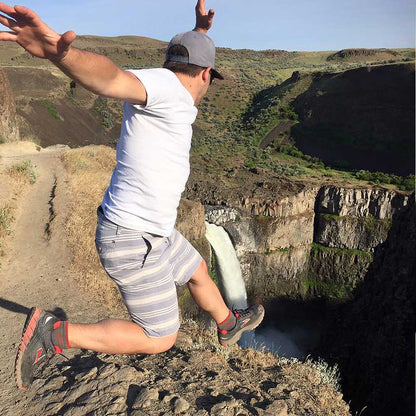 Hiker jumping for joy wearing Cloudline Cloudline 1/4 Top Running Sock above epic waterfall