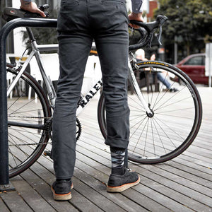 Biker in dress clothes locking bike to rack while wearing Cloudline socks. 