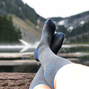 Hiker waring Cloudline compression socks laying with feet on log with mountain lake in background. 