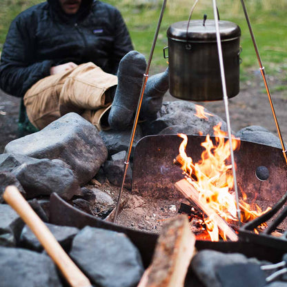 Man sitting by campfire wearing Cloudline hiking socks. 