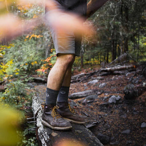 Hiker wearing Cloudline hiking socks standing on log bridge. 