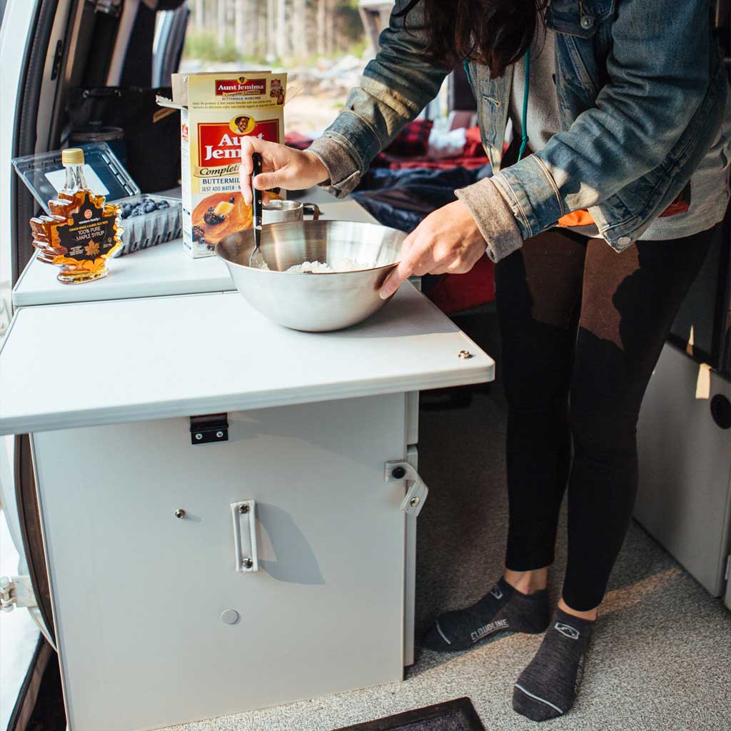 Women making breakfast in camper van wearing Cloudline running socks and without shoes. 