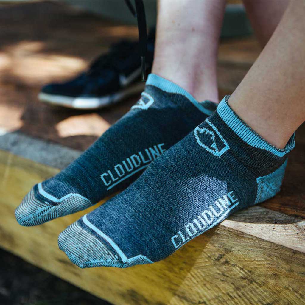 Women wearing Cloudline running socks sitting on wooden porch with shoes off. 