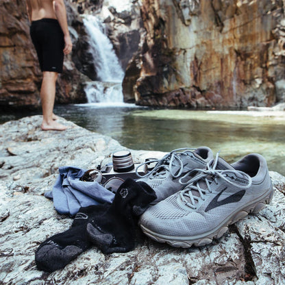 Hiker about to go for a swim with Cloudline running socks sitting on shoes and shirt. 
