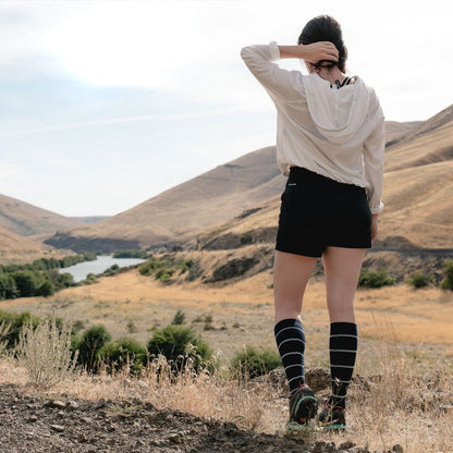 Women wearing Cloudline compression socks with back to camera looking at river and mountain view. 