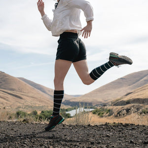 Women mid stride while trail running wearing Cloudline compression socks.  