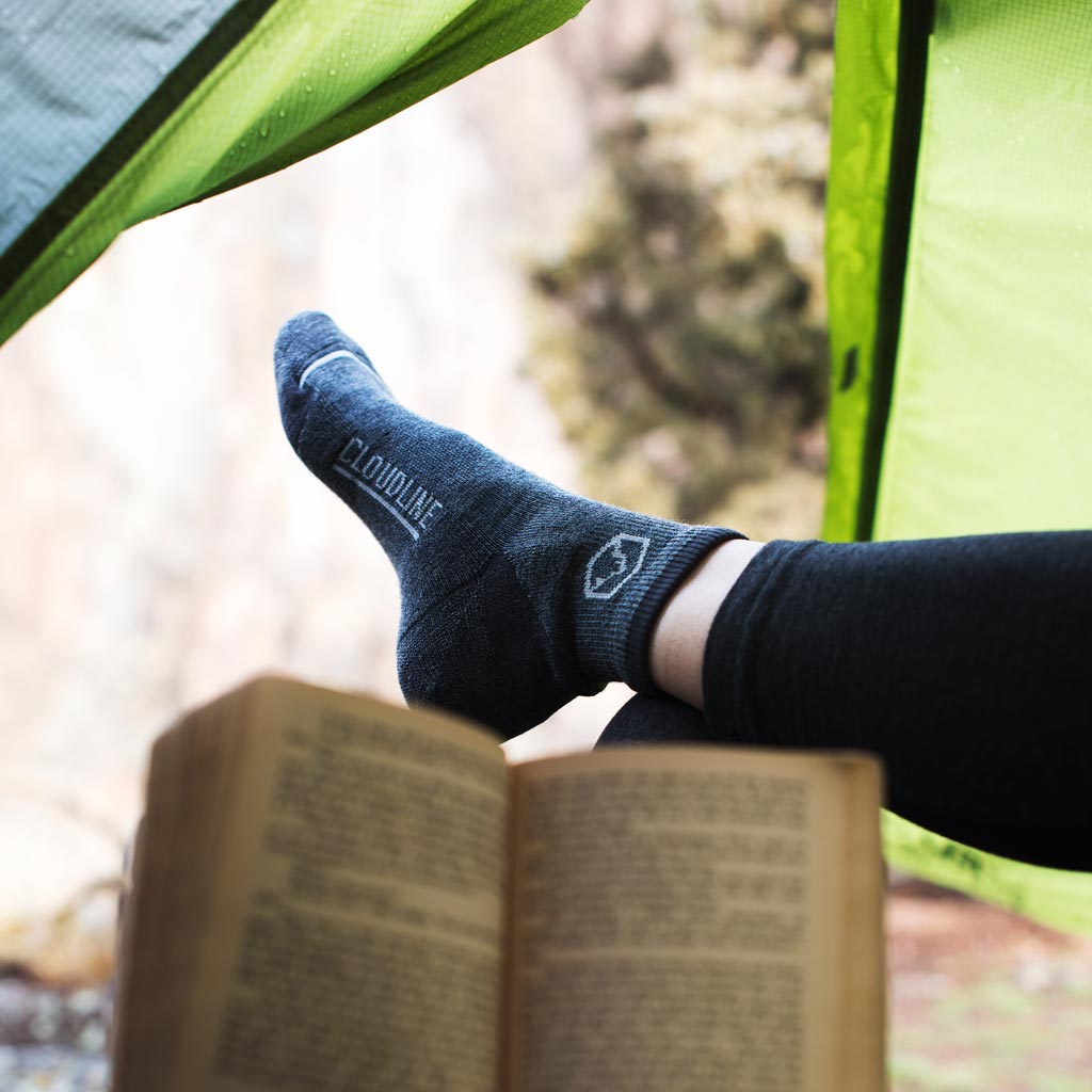 Camper reading in tent wearing Cloudline 1/4 Top Running Sock 