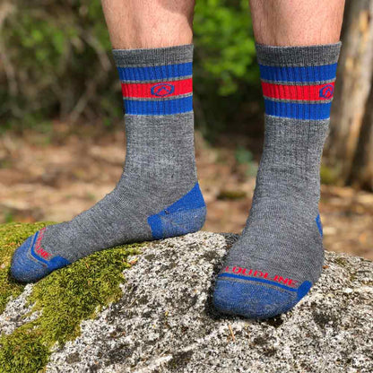 Hiker wearing Cloudline socks standing on mossy rock with shoes off.