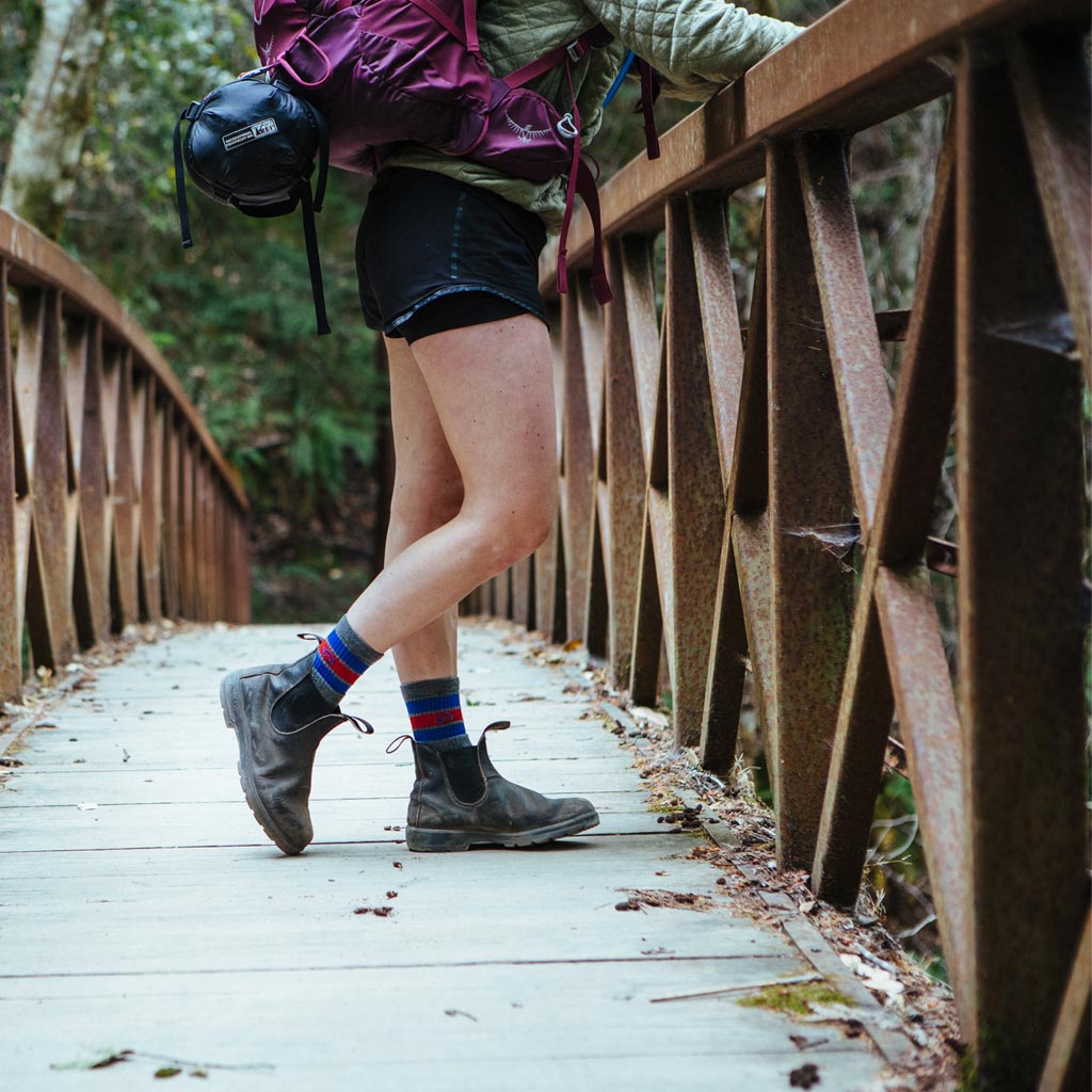 Women wearing Cloudline hiking socks while backpacking standing on wood bridge.
