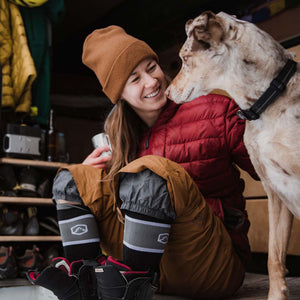 Snowboarder wearing Cloudline snowboard socks sitting in camper van petting dog.