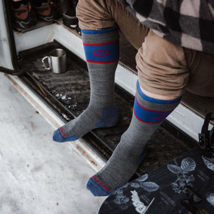 Man wearing Cloudline snowboard / ski socks sitting in camper van door next to snowboard.