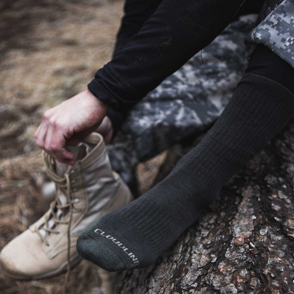 Man wearing Cloudling tactical socks putting on boots. 