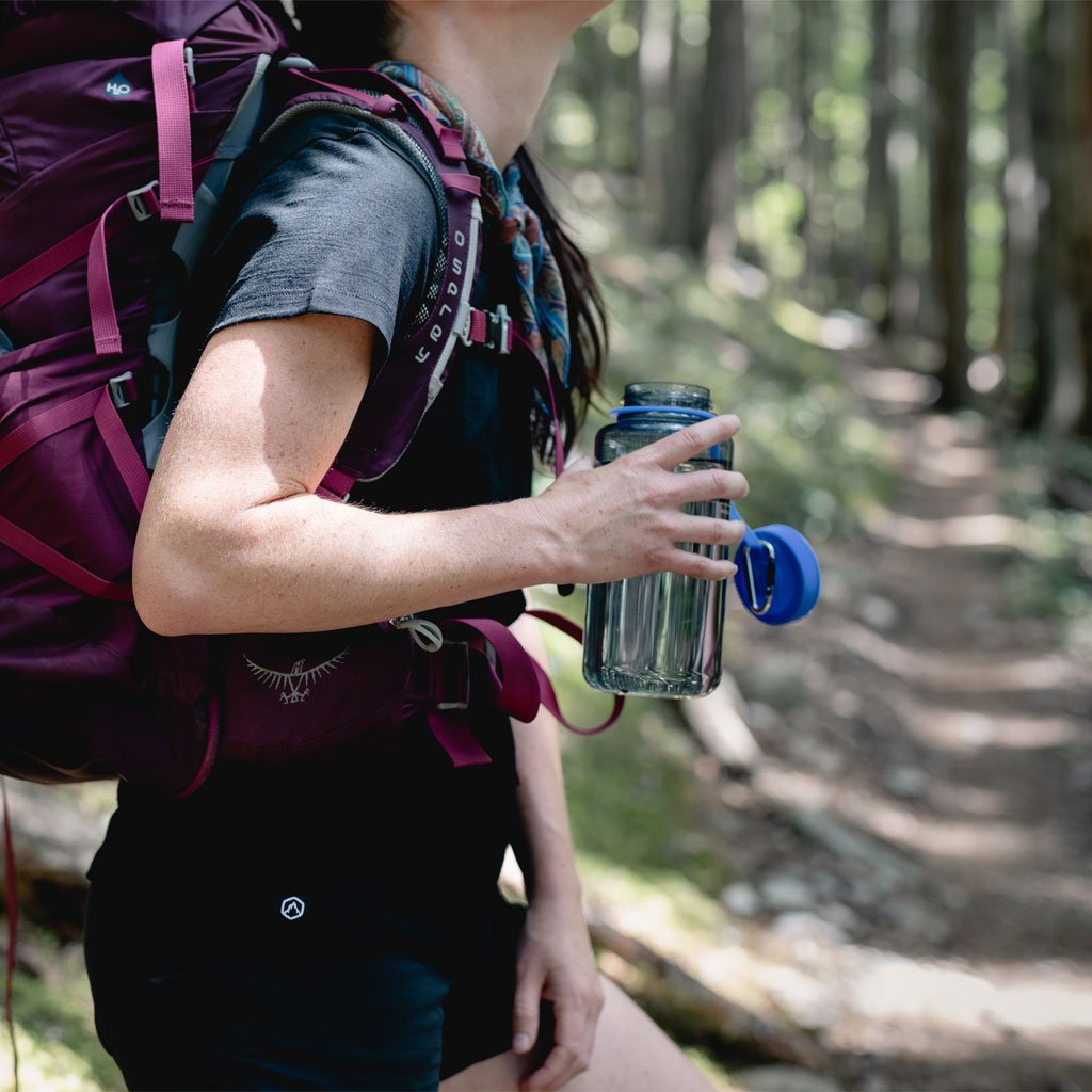 Backpacker wearing Cloudline merino shirt holding water bottle.